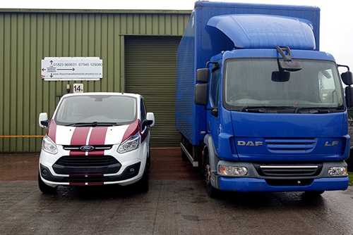 A branded van and large blue lorry parked outside a Somerset Removal Company warehouse